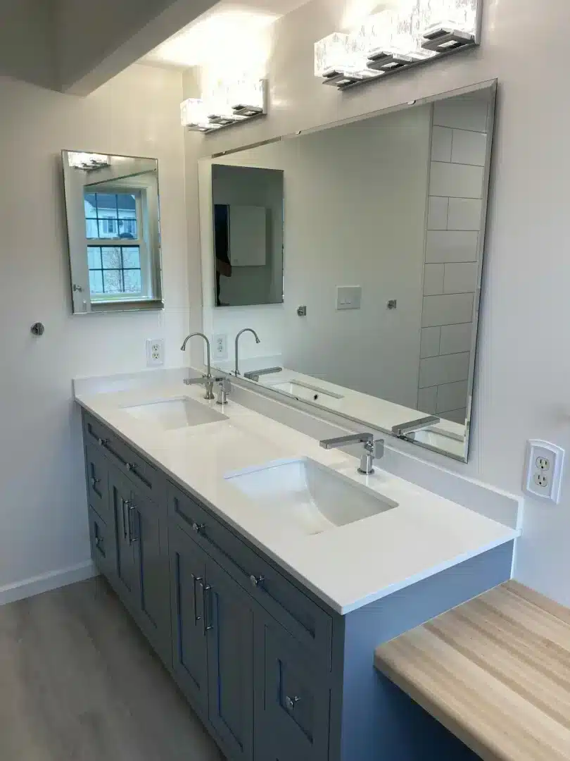 Blue double vanity with a white countertop and large mirror in a remodeled bathroom