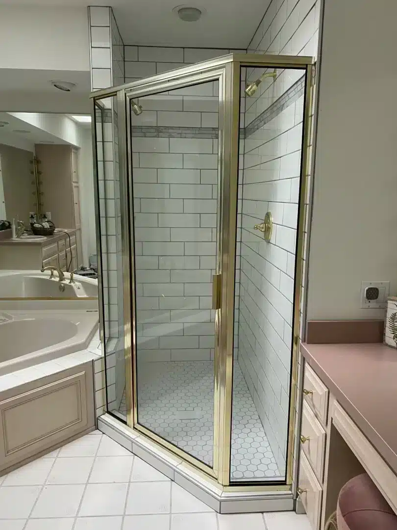 Corner glass shower enclosure with subway tile beside a soaking tub