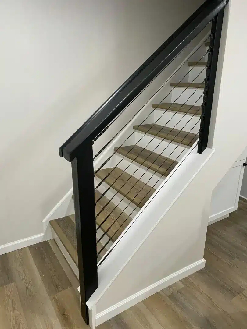 New staircase with a black railing and cable balusters leading to a finished basement